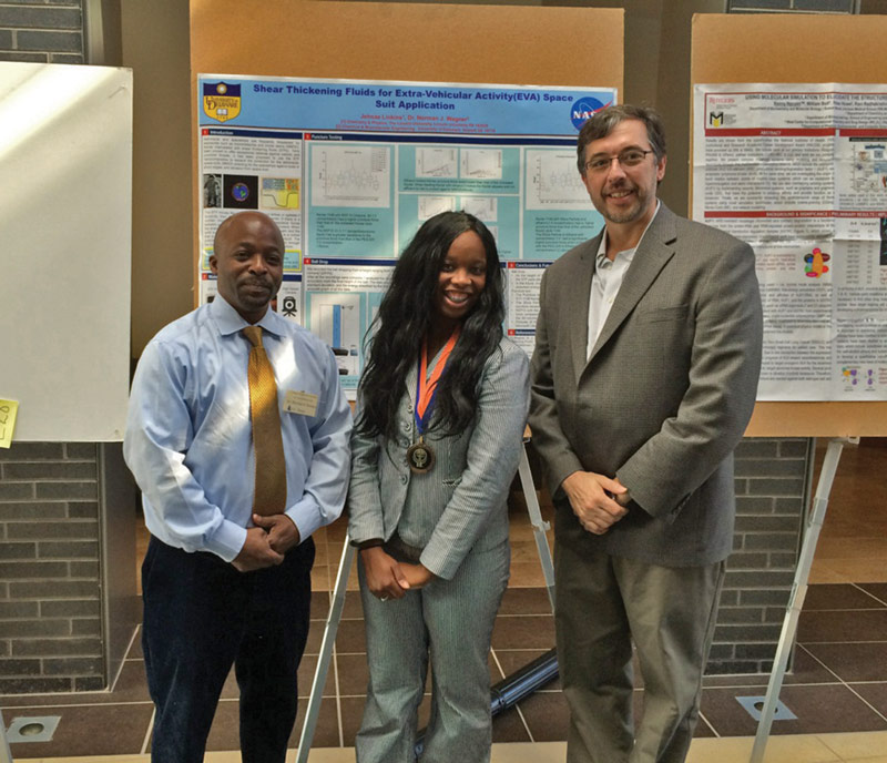 Jehnae (center) poses with Dr. Dean Swinton (left) and Dr. Norman Wagner (right) in front of a poster documenting her work on the NASA project. Photo courtesy of Jehnae Linkins.
