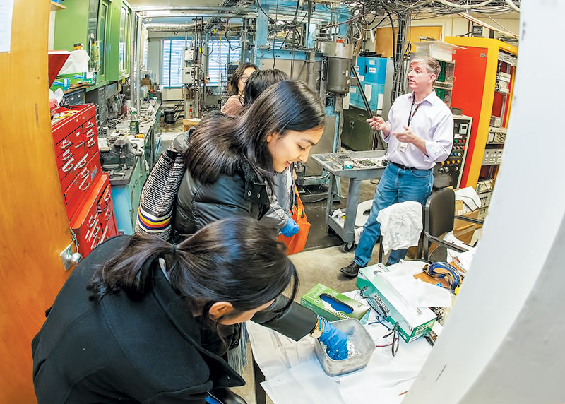 Camila López Pérez (center) and Shanjida Khan (foreground) observe Galinstan, a compound made of gallium, indium, and tin, during the Princeton Plasma Physics Laboratory tour. Photo courtesy of Elle Starkman.