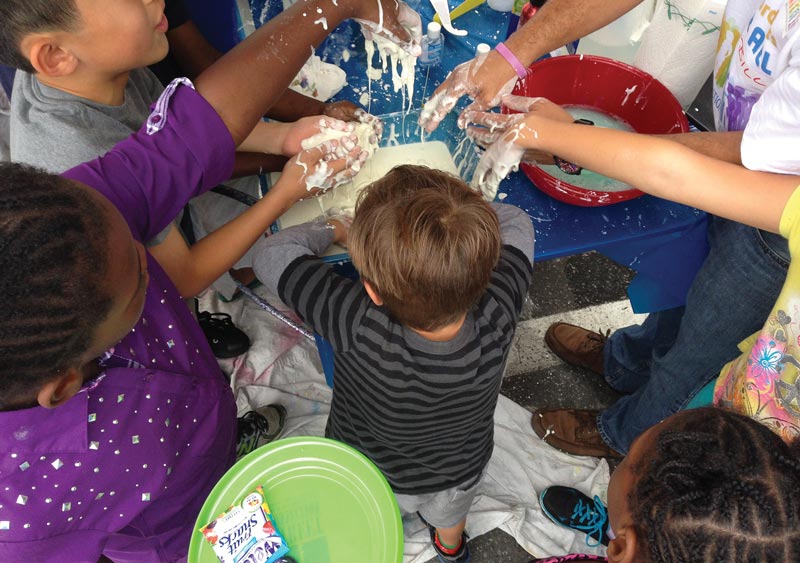 At the SPS booth, children learn about the properties of non-Newtonian fluids by playing with Oobleck, a mixture of cornstarch and water. Photo by Matt Payne.