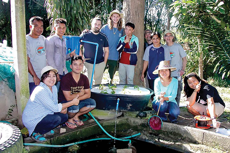On a recent trip to the Fang district in Thailand, Baker (back row, right) and two students from William Jewell College helped villagers construct an aquaponics system out of an existing catfish pond. Local plants placed in the floating raft draw nutrients from the water in the pond and help to filter the pond. Photo by Jeff Buscher.