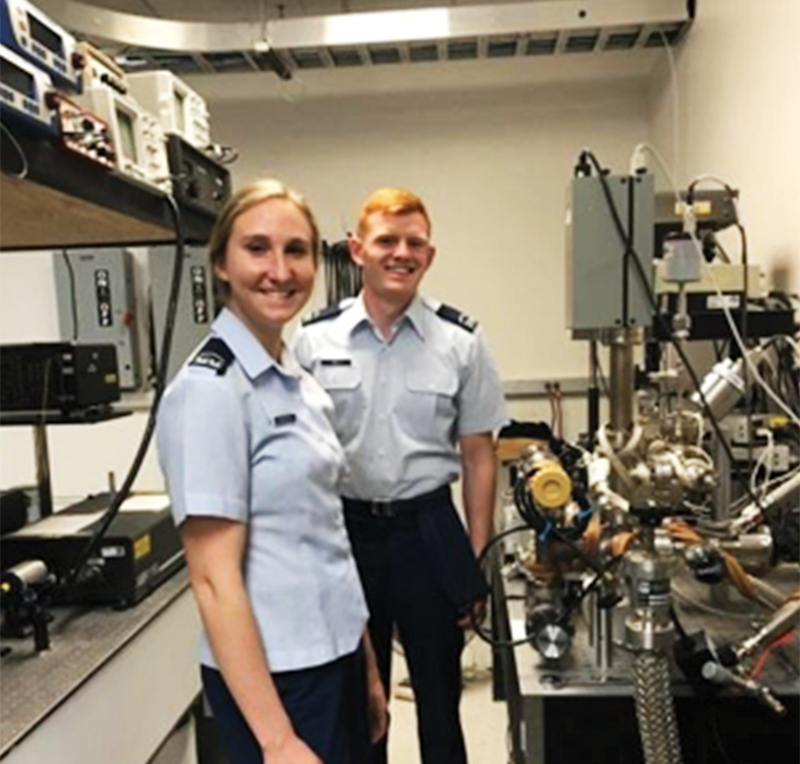 Cadets Lucy Zimmerman and Philip Rich posing in front of the vacuum system while adjusting the buffer gas pressure in preparation for collecting the fluorescence photons. All photos courtesy of Dr. Alina Gearba-Sell. 