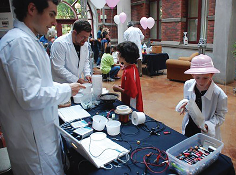 Table at a Science Open House. Building a speaker using wires, magnets, and a plastic yogurt tub and building the world's simplest motor. Photo by Brandy Todd.