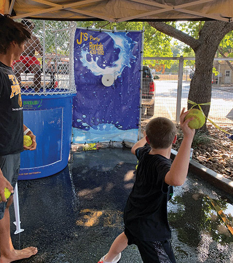 An attendee gets ready to send the dunk tank volunteer for a swim.