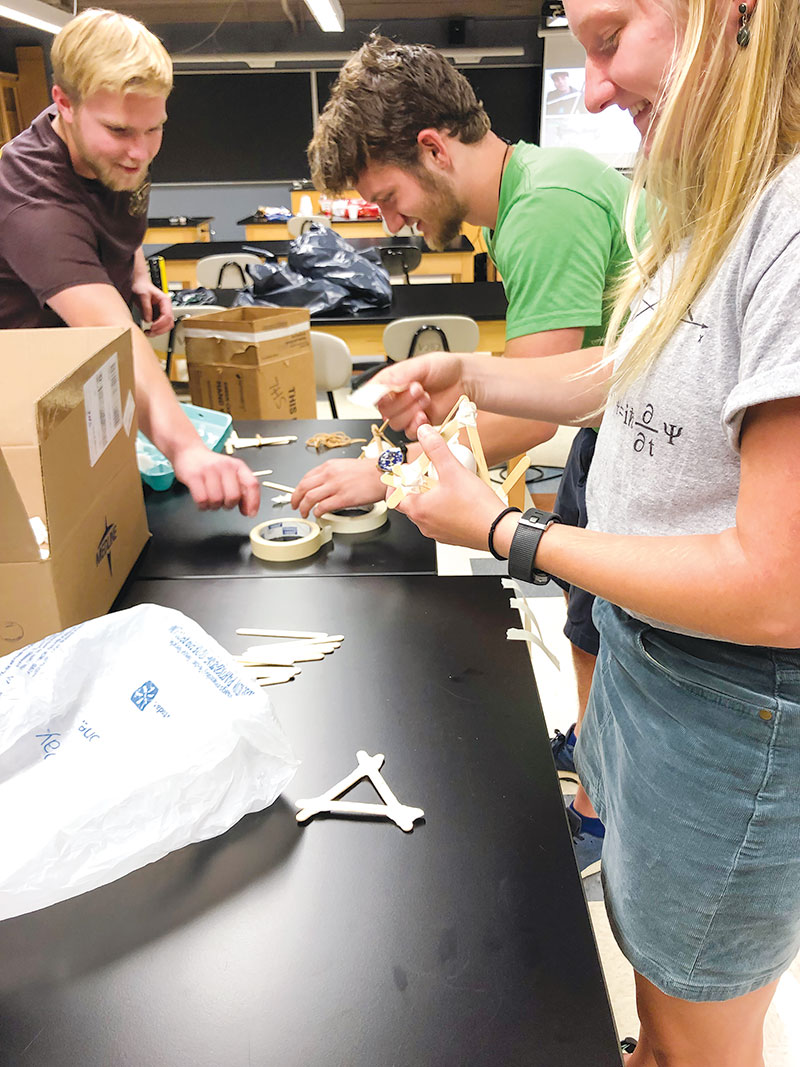 SPS chapter leaders (L–R) Dalton Ludington, Owen Johnson, and Abbigail Fahrenkamp build contraptions for an egg-drop contest. Photo by Erin Flater.