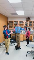 Middle schoolers try out a rotating platform demonstrating the conservation of angular momentum. 